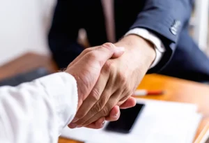 Two men shaking hands over office desk